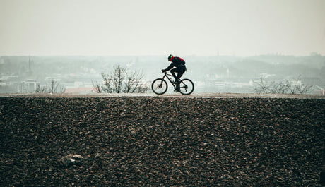 a man wearing a helmet rides a bicycle on the road