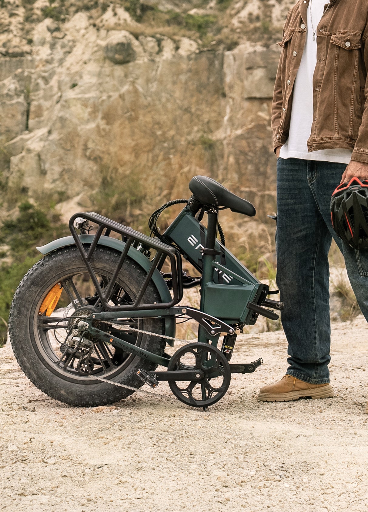 a man stands next to a folded sea green engwe engine pro 2.0 e-bike